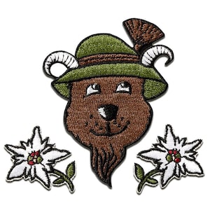 Op de afbeelding: Geborduurde patch met een bruine beer met een groene hoed met hoorns en een bruine baard. Twee witte en groene edelweissbloemen flankeren de beer. De patch staat op een witte achtergrond.