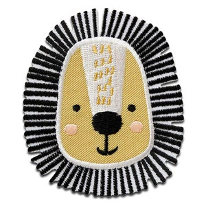 Könnte beinhalten: Ein gelbes Löwenkopf mit schwarzen Augen und einer rosa Nase, gestickt auf einem schwarz-weiß gestreiften Stoff. Die Löwenmähne besteht aus schwarzen und weißen Streifen.