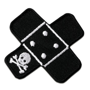 Könnte beinhalten: Schwarzer Stoff-Patch mit einem weißen gestickten Design eines Verbandes mit Totenkopf und Knochen. Der Verband hat weiße Punkte.