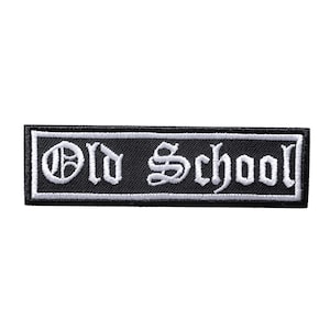 Può includere: Toppa rettangolare nera con testo ricamato bianco "Old School" in un carattere gotico. La toppa ha un bordo bianco ed è progettata per essere cucita o stirata su vestiti o accessori.