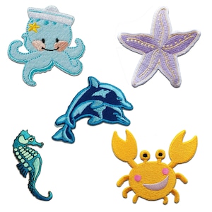 Può includere: Set di sei toppe termoadesive colorate con motivi di creature marine. Le toppe includono un polpo blu con un cappello da marinaio, una stella marina viola, un delfino blu, un cavalluccio marino blu e un granchio giallo.