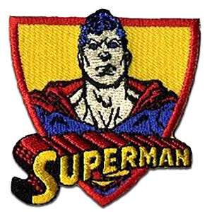 Op de afbeelding: Geborduurde patch met Superman in een schildontwerp. De patch heeft een gele achtergrond met een rode rand. Superman wordt afgebeeld met blauw haar en een rood en blauw kostuum. Het woord "SUPERMAN" staat in gele en rode letters.