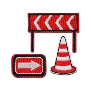 Può includere: Tre toppe ricamate in ferro rosso e bianco: una barriera stradale con segni a chevron, un cono di segnalazione e un cartello con freccia direzionale.