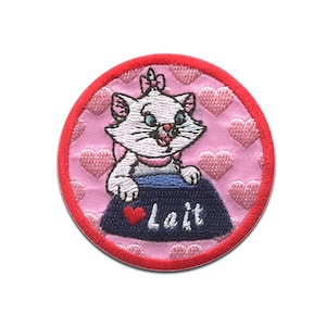 Peut inclure: Un patch brodé rose et rouge avec un chat blanc tenant un bol bleu qui dit "Lait" avec un cœur rouge. Le fond est rose avec des cœurs blancs.