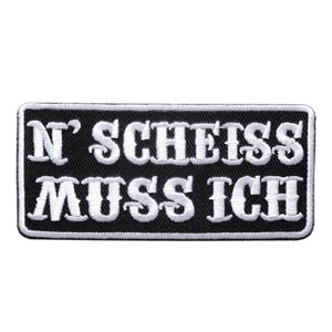 May include: Black rectangular patch with white embroidered text that reads "N' SCHEISS MUSS ICH". The patch has a white border and is likely designed to be sewn onto clothing or accessories.