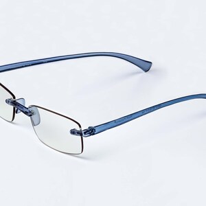 Puede incluir: Gafas de lectura sin montura azules con lentes transparentes. Las gafas tienen una montura flexible y est&aacute;n hechas de pl&aacute;stico.