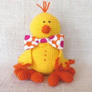 poussin jaune au crochet avec bec et pattes oranges. noeud papillon fleuri assortie