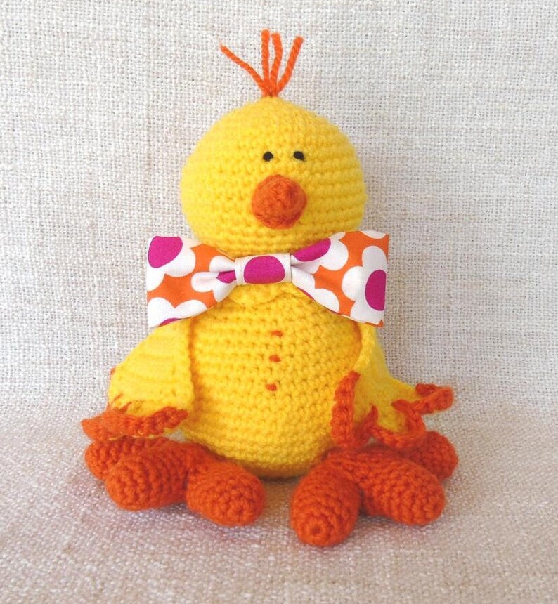 poussin jaune au crochet avec bec et pattes oranges. noeud papillon fleuri assortie