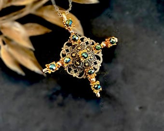 May include: A gold-toned pendant necklace featuring an intricate filigree cross design. The center and four arms are adorned with small, iridescent dark green beads. The metalwork displays a detailed, openwork pattern suspended from a thin chain.