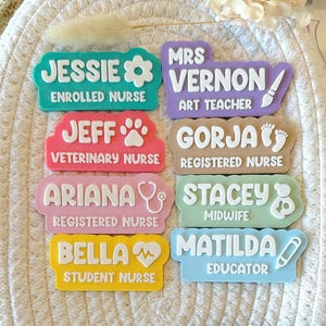 May include: A selection of colourful name tags, each displaying a name and profession. Examples include "Jessie, Enrolled Nurse" and "Mrs. Vernon, Art Teacher." The tags are in shades of pink, blue, green, yellow, and purple, with white text.