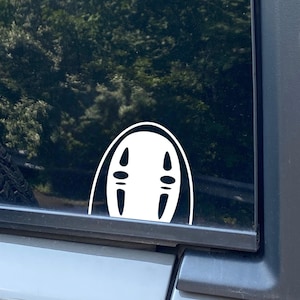 May include: White vinyl sticker of No Face from the animated film Spirited Away, applied to the rear window of a car.