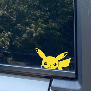 May include: A yellow Pikachu cartoon character peeking out from behind a car window.