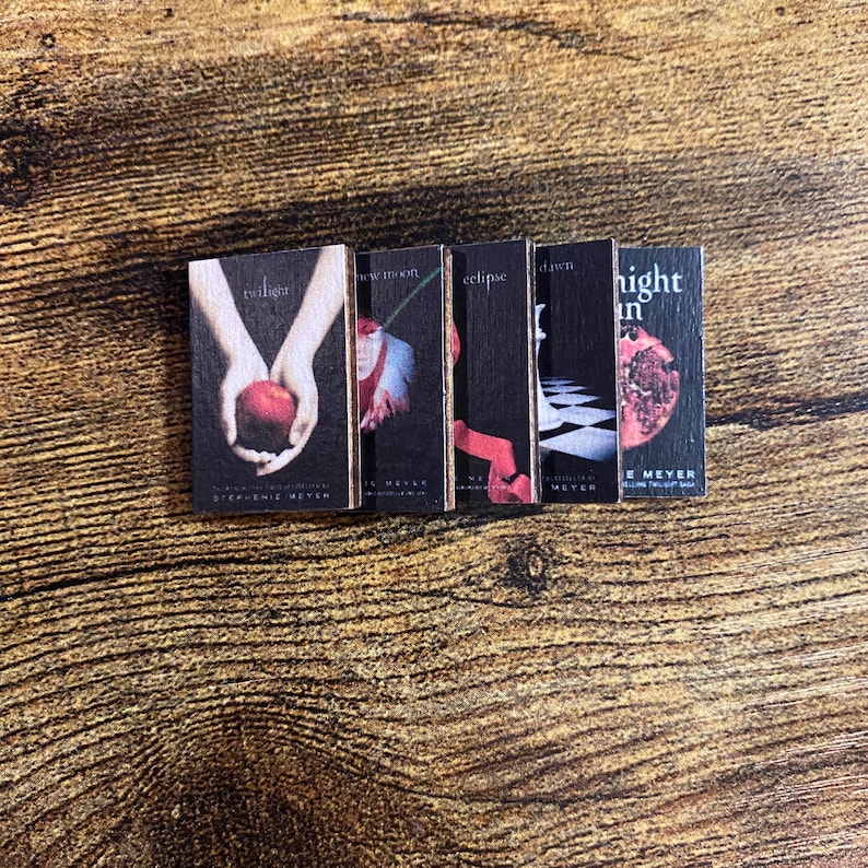 May include: A set of five paperback books with black covers and colorful images. The titles are "Twilight", "New Moon", "Eclipse", "Breaking Dawn", and "Midnight Sun".