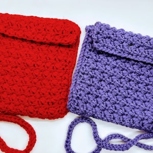 May include: Two crocheted crossbody bags, one red and one purple. Both bags have a flap closure and a long strap.