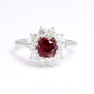 May include: A silver ring with a large red ruby surrounded by a halo of smaller diamonds.