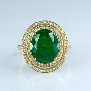 以下が含まれることがあります： ダイヤモンドの小さな二重の輪で囲まれた大きなエメラルドの宝石が付いた金の指輪