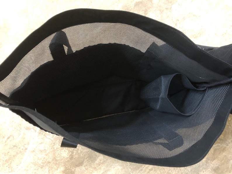 May include: Black mesh tote bag with a zippered pocket on the inside. The bag has a black fabric lining and a black handle.