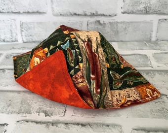May include: A folded orange and green fabric with a fishing theme. The fabric features a pattern of fish, reeds, and other fishing-related imagery.