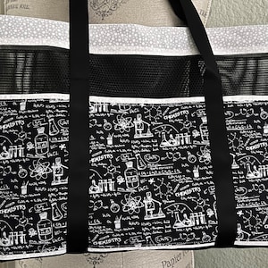 May include: Black and white tote bag with a mesh pocket and a white and grey polka dot trim. The bag features a repeating pattern of chemistry-related illustrations, including beakers, flasks, atoms, and chemical formulas. The text "CHEMISTRY" appears multiple times on the bag.