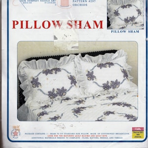 Puede incluir: Una funda de almohada blanca con un borde con volantes y orquídeas bordadas en tonos morados y azules. La funda de almohada está hecha de algodón y tela ancha de polialgodón y está diseñada para adaptarse a una almohada de tamaño estándar. El paquete contiene una funda de almohada e instrucciones para completar el proyecto. El texto en el paquete dice "Jack Dempsey Needle Art, Since 1949, St. Louis, MO. Item 1200, Pattern #297, Orchids, Pillow Sham".