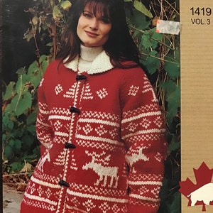 Puede incluir: Un cárdigan de punto rojo y blanco con un patrón de copos de nieve y renos. El cárdigan tiene un cuello blanco y botones en la parte delantera. La imagen es de White Buffalo The Canadian Yarn, Vol. 3, patrón número 1419.