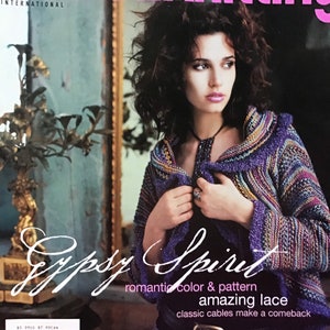 May include: Vogue Knitting magazine cover featuring a model wearing a purple and multi-coloured crocheted jacket with a Gypsy Spirit theme. The text on the cover reads "romantic colour & pattern amazing lace classic cables make a comeback".