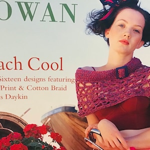 May include: A book cover featuring a woman wearing a crocheted shawl with a buckle. The book title is "Beach Cool" and the text below reads "Over Sixteen designs featuring Linen Print & Cotton Braid by Lois Daykin".
