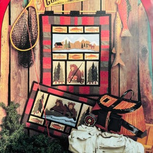 May include: A quilt pattern featuring a red and black plaid background with a scene of a cabin in the woods, bears fishing, and a sign that reads "Gone Fishin'"  The pattern is from Calico Garden Patterns.