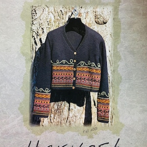 Op de afbeelding: Een marineblauwe gebreide cardigan met een V-hals, gouden knopen en kleurrijke patroonafwerking. De afbeelding bevat de tekst "Mission Falls" en "Harvest" met "Fall 2001" weergegeven. Het ontwerp is van mags Kandis.