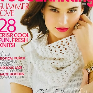 Puede incluir: Portada de la revista Vogue Knitting con una mujer que lleva un suéter de cuello alto de punto blanco con el texto "Black & White Sheer Magic" en la portada.