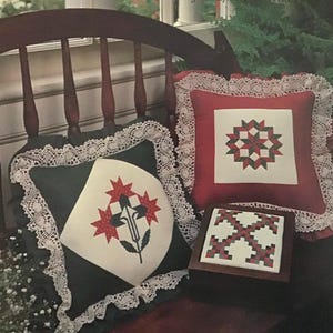 May include: A Quilter's Delight Vol. 1 Country Crafts by Walter leaflet. Two pillows with red, green, and white patchwork designs. One pillow has a white lace trim. A small wooden box with a red, green, and white patchwork design.