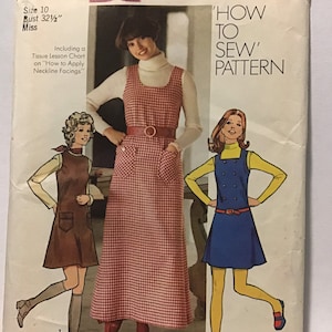 May include: Simplicity sewing pattern number 5203, 'How to Sew' pattern, for sizes 10, 12, 14, 16, 18, 20, 22, 24, and 26. The pattern includes instructions for making three different styles of dresses: a brown dress with pockets, a red and white gingham dress with a belt, and a blue dress with buttons.