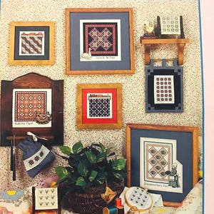 May include: A collection of eight framed cross-stitch patterns featuring various quilt designs. The patterns include "Goose in the Pond", "Robin's Nest", and "Grandmother's Fan". The title of the collection is "Quilted Delights" by Kristy Goodin Soard.