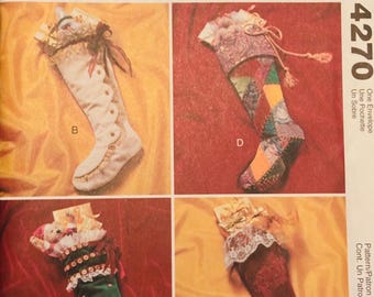 May include: A McCall's Crafts pattern featuring four Christmas stocking designs. The stockings are in various colors, including white, green, and red, with decorative elements like lace, buttons, and bows. The pattern number is 4270.