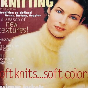 Könnte beinhalten: Vogue Knitting Magazin-Cover mit einer Frau, die einen weichen, hellgelben Strickpullover trägt. Der Covertext lautet "Tradition neu definiert" und "eine Saison mit neuen Texturen!" mit dem Slogan "weiche Strickwaren...weiche Farben".