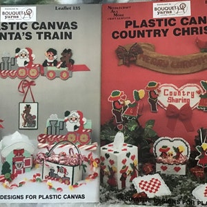 May include: Two plastic canvas craft leaflets with Christmas themes. The first leaflet features a Santa's train and the second leaflet features a country Christmas theme with a banner that reads "Merry Christmas". Both leaflets feature a variety of plastic canvas projects.