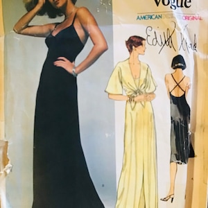 May include: A vintage sewing pattern for a long, flowing gown. The pattern is from Very Easy Vogue and features a black gown with a plunging neckline and a yellow gown with a wrap-style neckline. The pattern is designed by Edith Head.