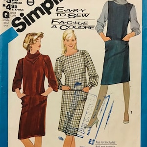 May include: Simplicity sewing pattern featuring three dress designs. The pattern includes options for a turtleneck dress, a plaid dress, and a sleeveless dress. The pattern is labeled "Easy to Sew" and includes sizing information.