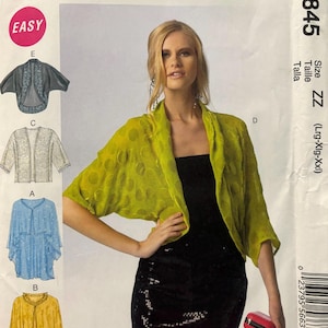 Puede incluir: Un patrón de costura para un bolero de mujer, con un bolero verde de lunares, una falda negra de lentejuelas y un bolso de mano rojo. El patrón es para las tallas grande, extra grande y extra extra grande. El patrón se llama McCall's M6845.