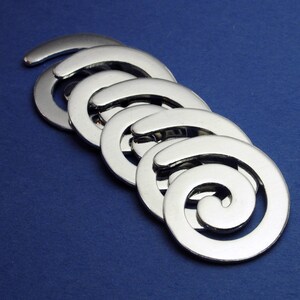 May include: A set of five silver metal spiral charms, each with a different size, arranged in a cascading pattern.