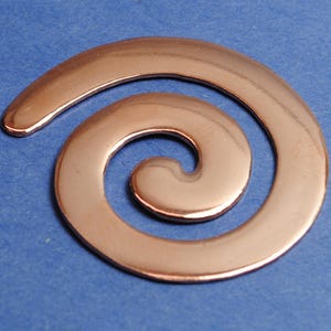 Op de afbeelding: Een koperkleurige metalen spiraalbedel met een gladde, glanzende afwerking.