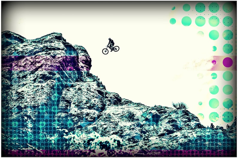 May include: A silhouette of a person riding a mountain bike over a rocky cliff. The background is a white sky with a blue and green polka dot pattern.