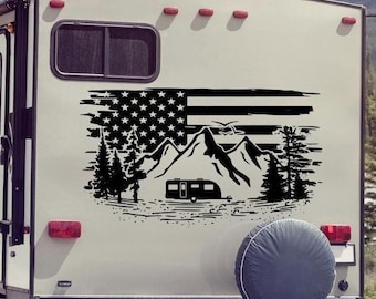 Puede incluir: Un adhesivo de vinilo negro aplicado en la parte trasera de un vehículo recreativo blanco. El diseño presenta una bandera estadounidense desgastada de fondo con una silueta de picos montañosos, pinos, una caravana y aves.