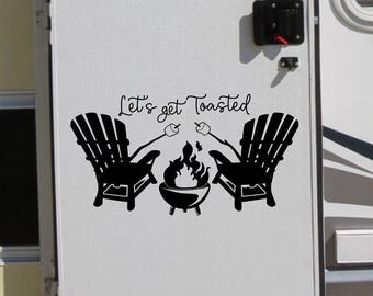 May include: A black vinyl decal applied to a white door featuring two Adirondack chairs facing a central fire pit with flames. Above the chairs, the text reads Let's get Toasted in a cursive script, with two marshmallows on sticks.