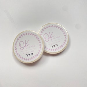 May include: Two rolls of white washi tape with a pink floral design and the text "OK PLANS WASHI TAPE 7x9" on each roll.