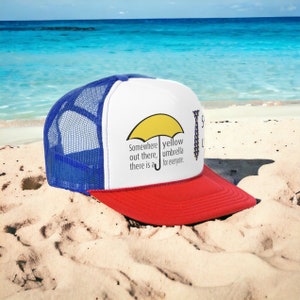 May include: A white, red and blue trucker hat with a yellow umbrella and the text "Somewhere out there, there is a yellow umbrella for everyone." on the front.