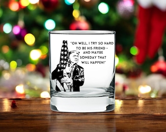 May include: A clear glass tumbler with a black and white image of a man holding an American flag. The text on the tumbler reads "OH WELL, I TRY SO HARD TO BE HIS FRIEND - AND MAYBE SOMEDAY THAT WILL HAPPEN!"