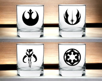 May include: Four clear glass tumblers with black Star Wars themed logos. The logos are the Rebel Alliance symbol, the Jedi Order symbol, the Mandalorian symbol, and the Galactic Empire symbol.