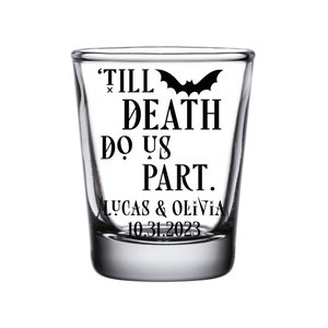 May include: A clear glass shot glass with a black bat and the text "Till Death Do Us Part. Lucas & Olivia 10.31.2023" printed on it.