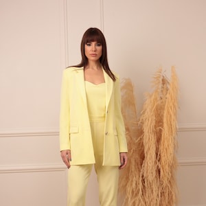 Elegant damespak in zachtgele kleur. jas en overall